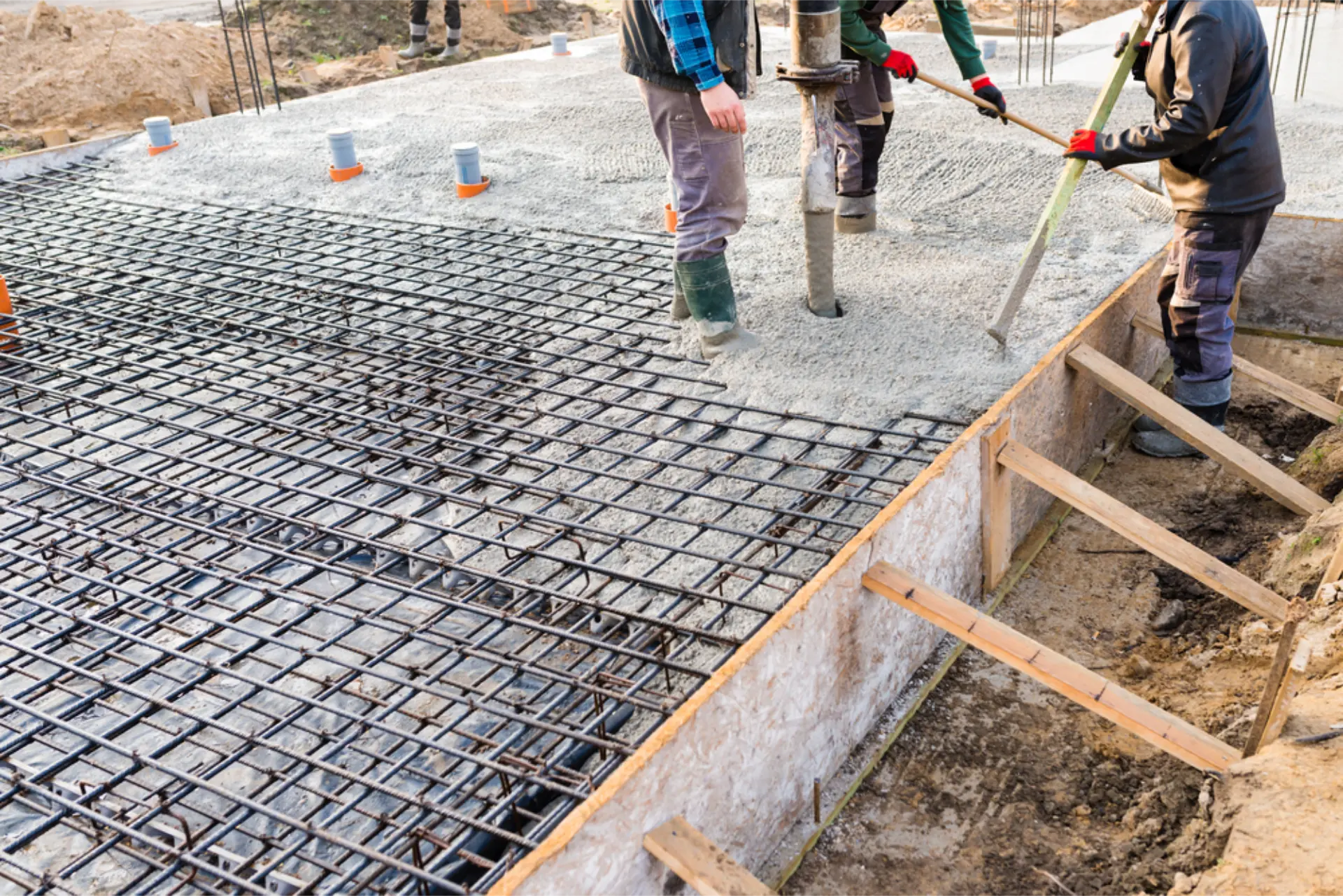 A harnessed worker trowel-finishing a concrete surface on site