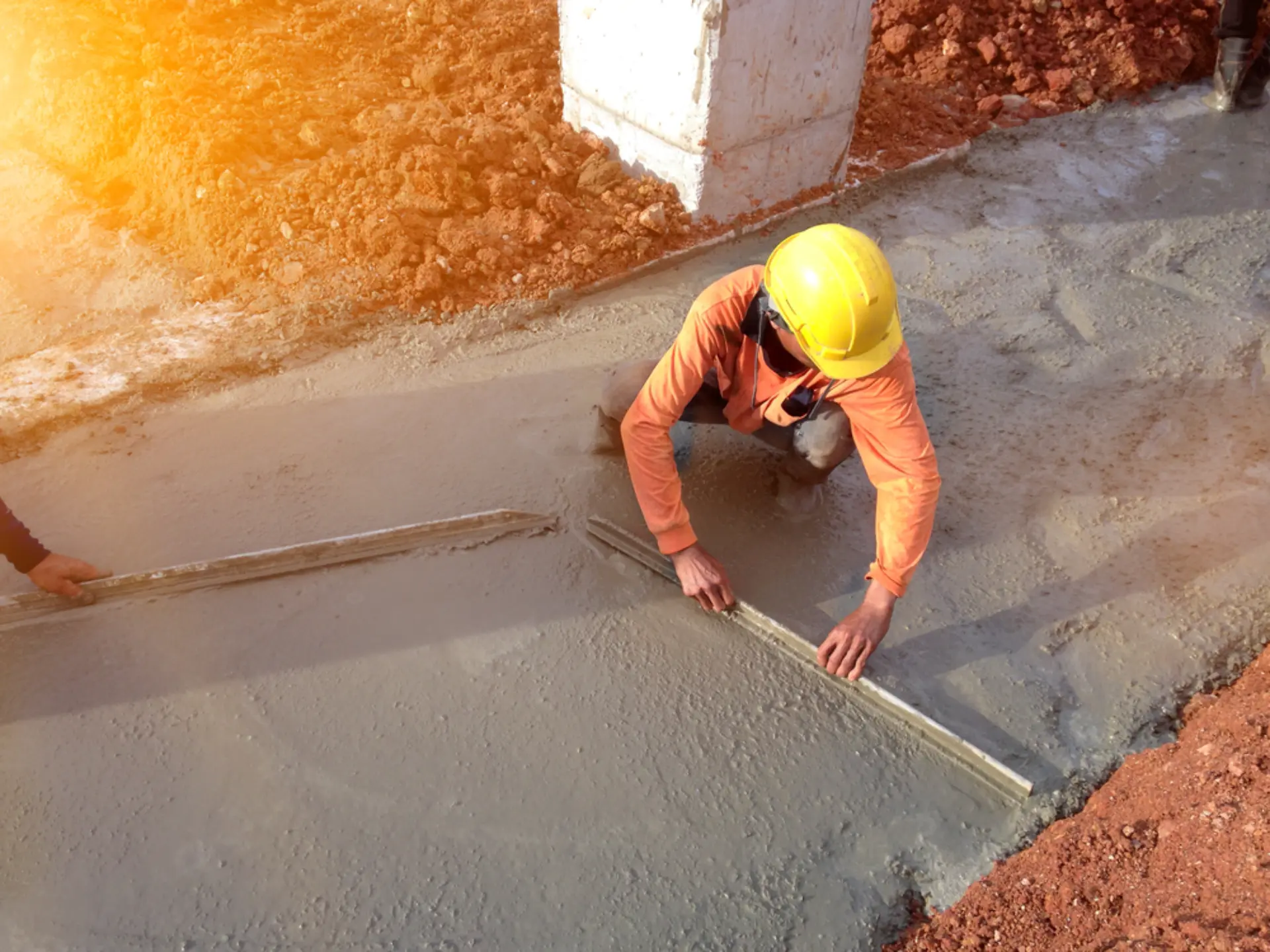 Aerial view of a crew and concrete pump truck working a slab on a red dirt block