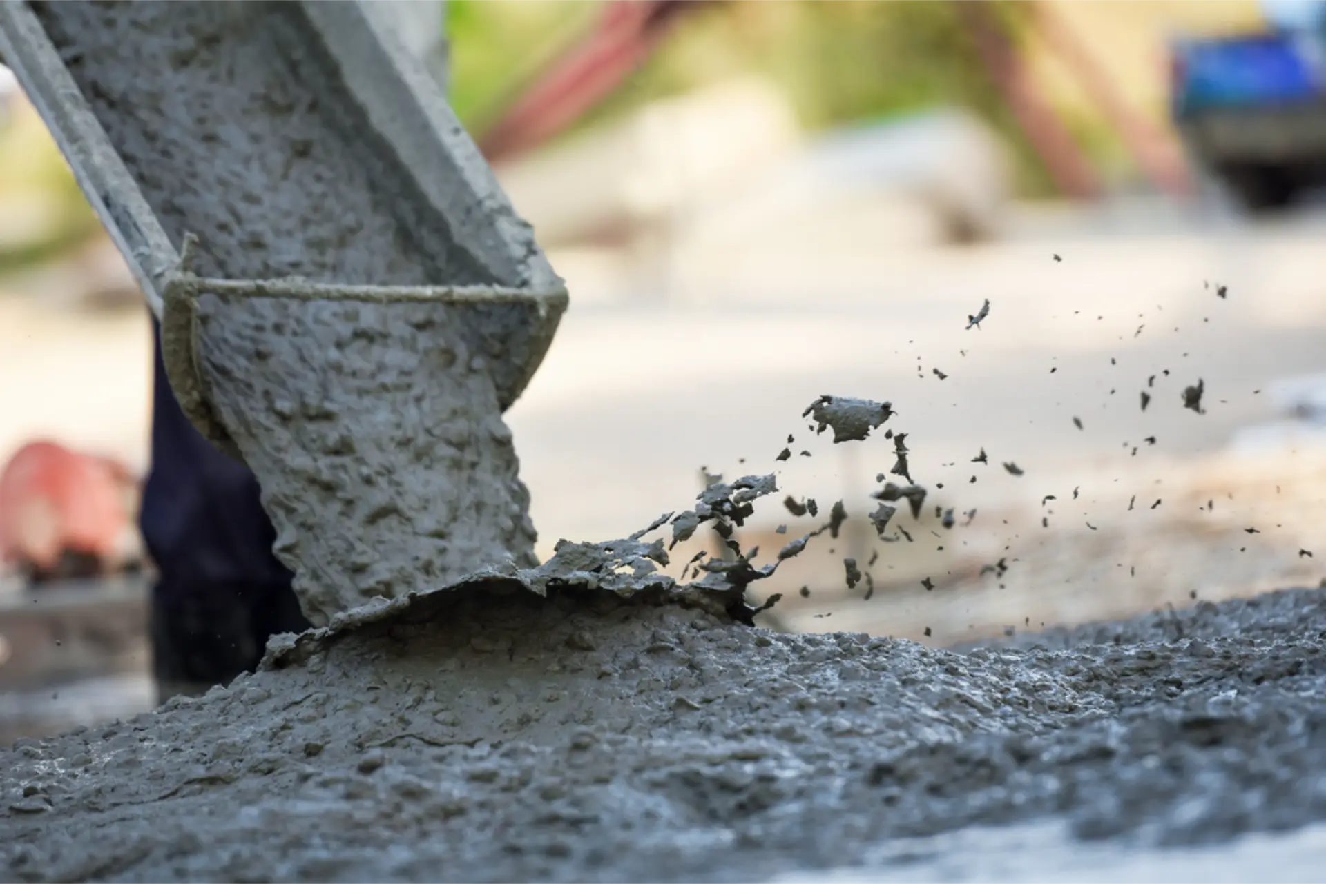 A crew working rakes across a sunlit concrete slab as it is placed