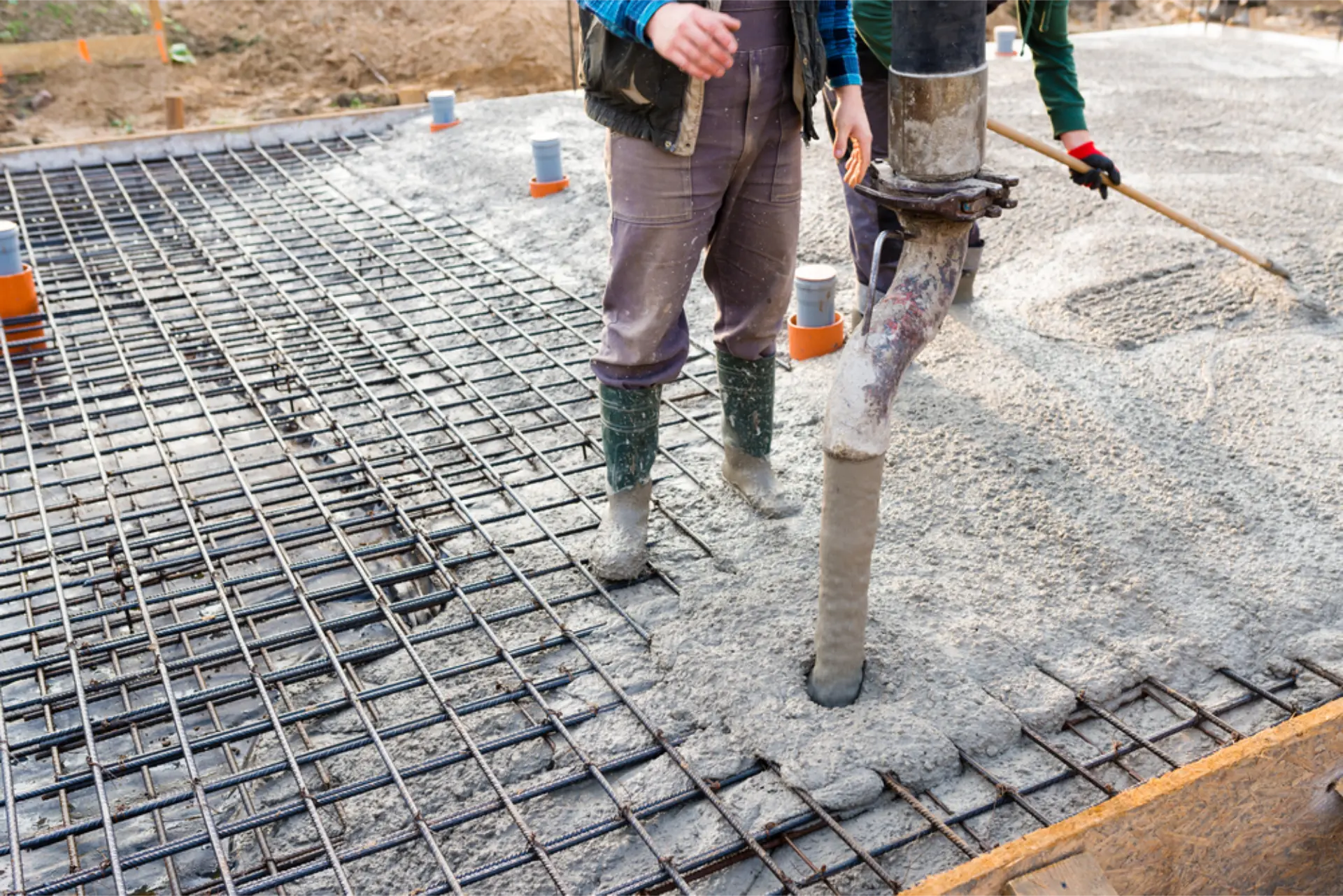 A crew raking concrete out across a large slab pour