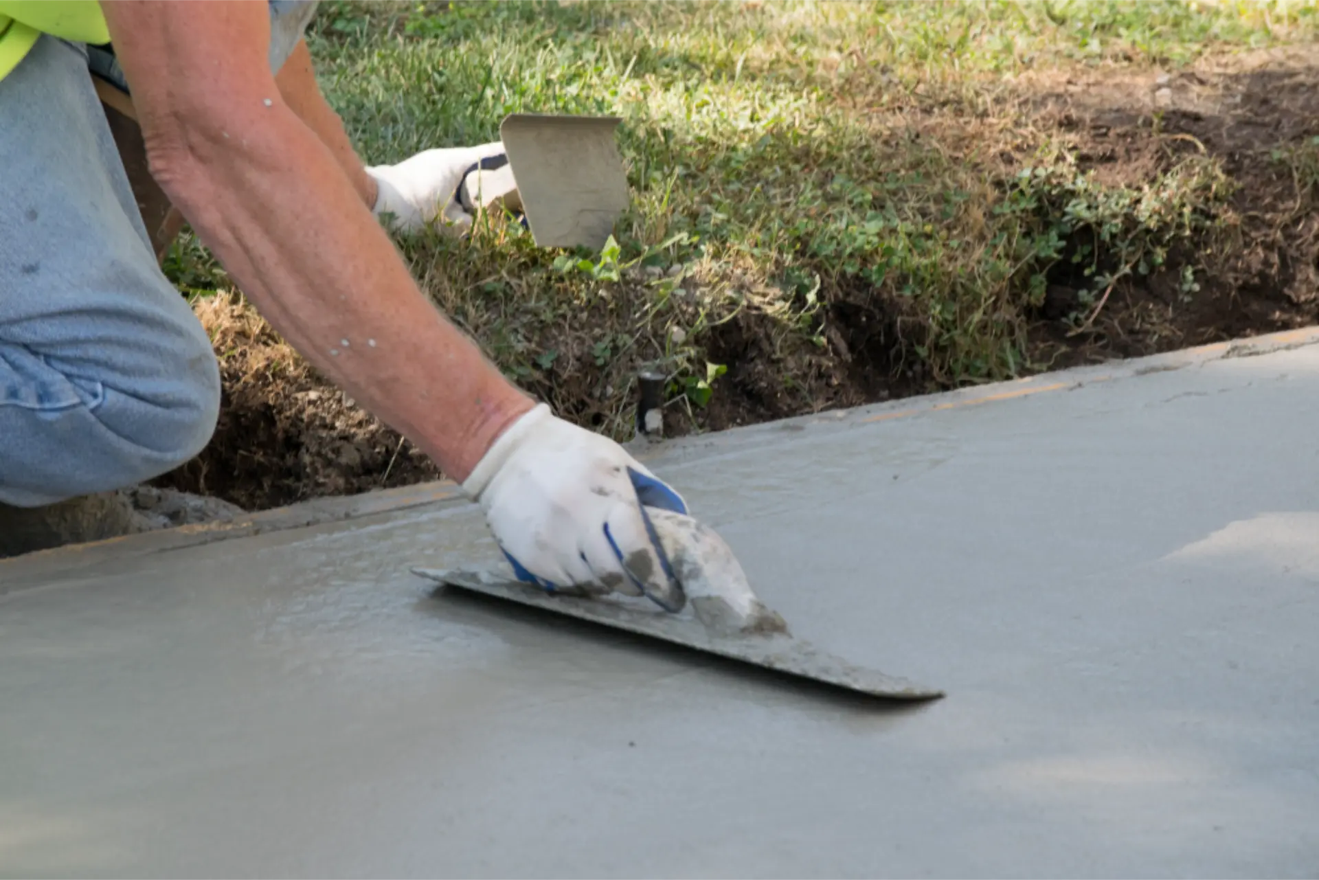 Hand trowelling the edge of a new concrete path against the lawn
