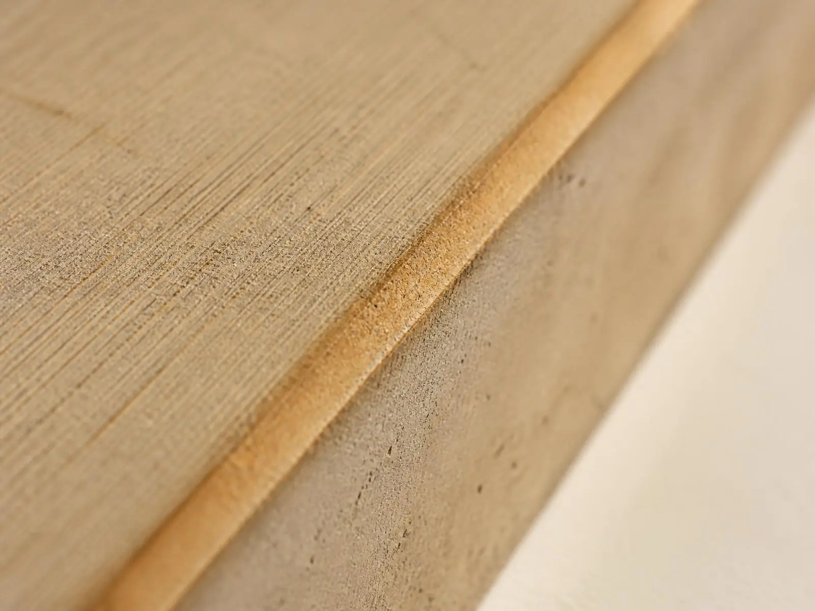 Close-up of a broom-finished concrete slab edge with a warm oxide tint